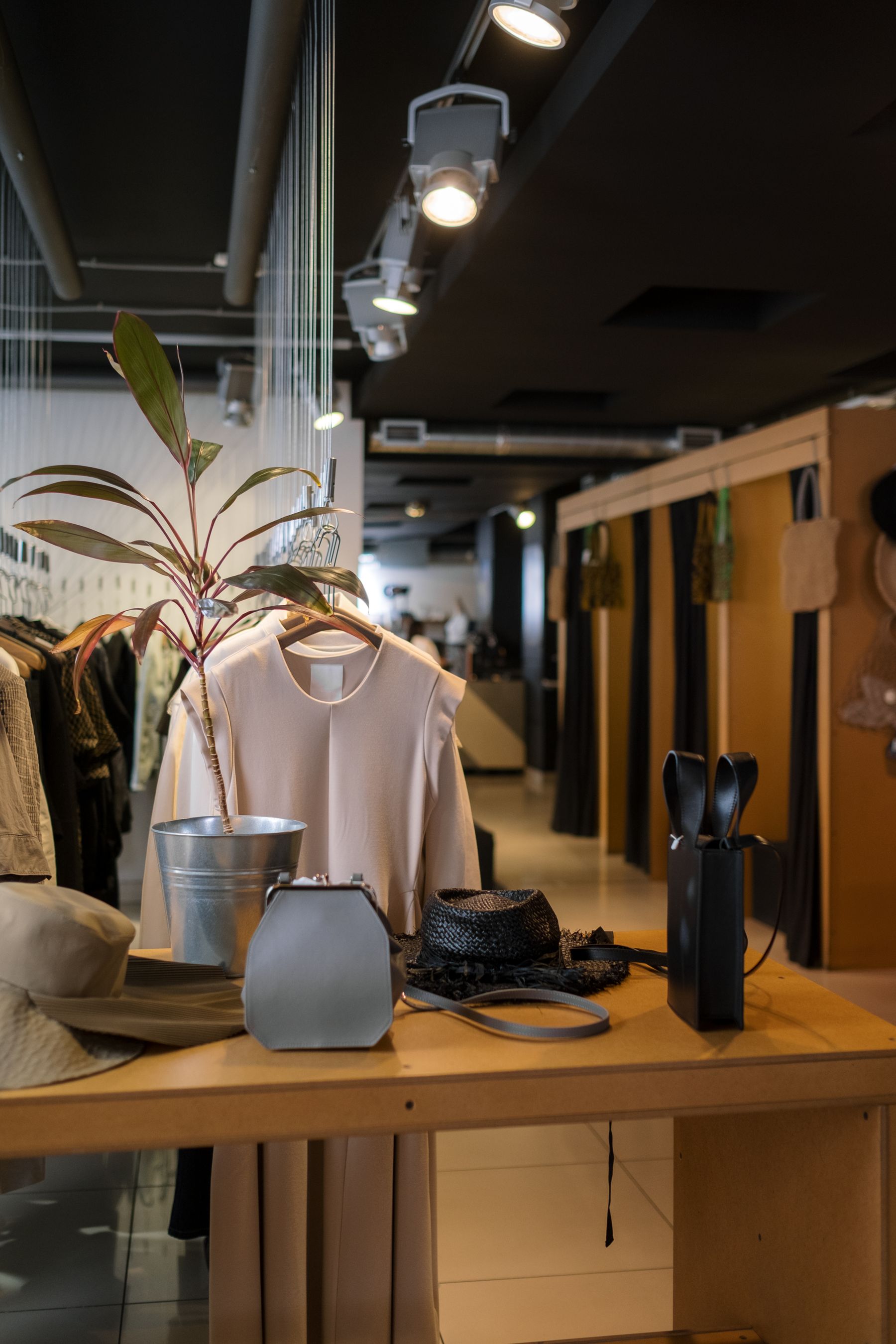 Clothing store with ceiling track lights above a central display table and clothing rails.