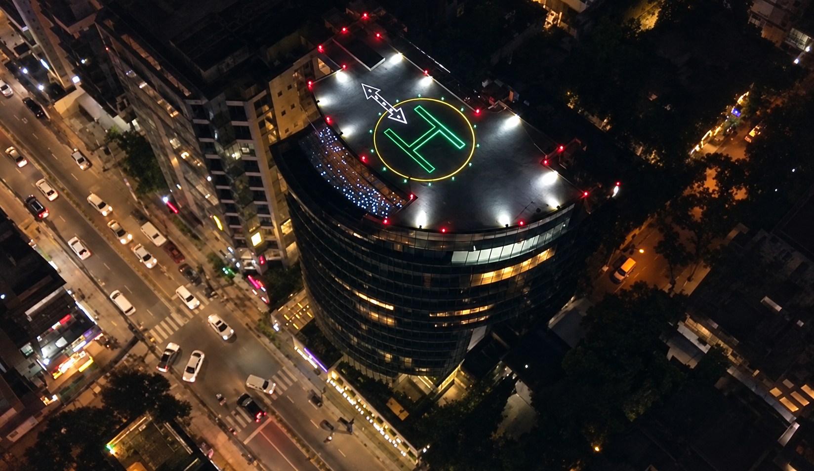 Sikder Haus and its illuminated rooftop helipad at night. Editorially enhanced photograph.